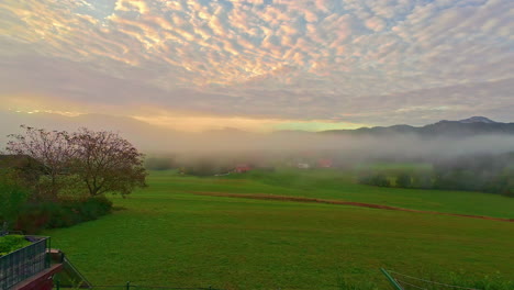 thin mist rolling over rural countryside below sunset sky, timelapse