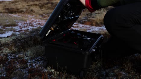 fotógrafo cerrando el contenedor de la cámara de tapa dura al aire libre en islandia
