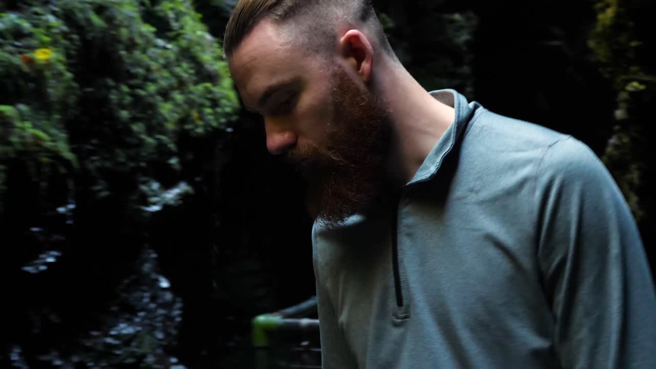 Ung mand går langsomt i et hulelignende sted og kigger ned, mens vand drypper.