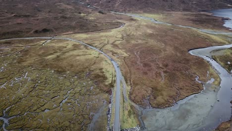 Aerial-dolly-flying-backwards-and-then-forwards-showing-off-the-middle-of-nowhere,-road-in-the-middle-and-lake-on-the-right-hand-side