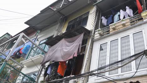 Traditional-Vietnamese-housing-and-balconies-with-flags-and-clothes-hanging-in-Old-Quarter-in-Hanoi,-Vietnam