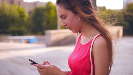 adolescente de moda enviando mensajes de texto en el teléfono mientras camina por la ciudad