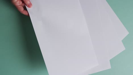 mano sosteniendo un pedazo de papel sobre pedazos de papel con espacio de copia en fondo verde en cámara lenta