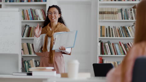 female teacher gives a lecture in a library or classroom setting