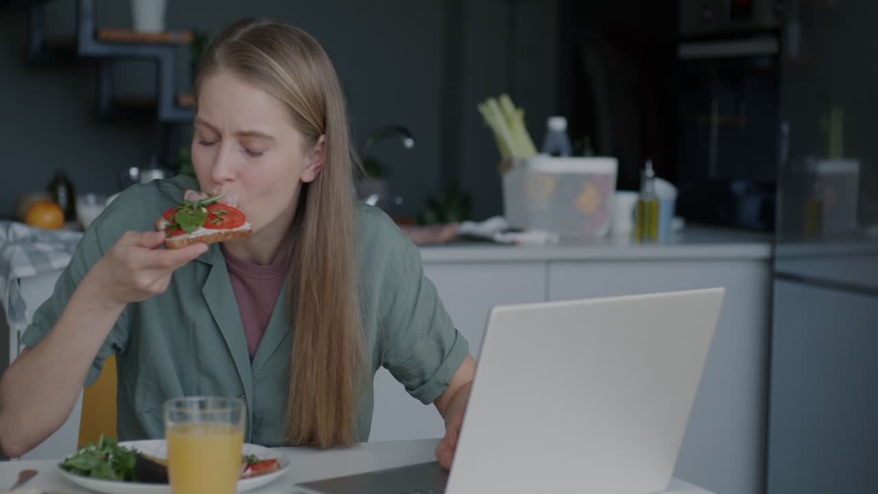 Woman eating sandwich while working from home