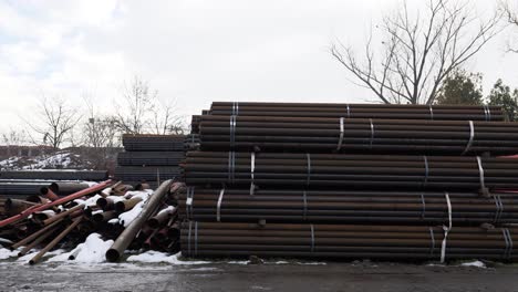 Round-Metal-Finished-Product-Warehouse-Near-Rusted-Pipes-Lying-Outside