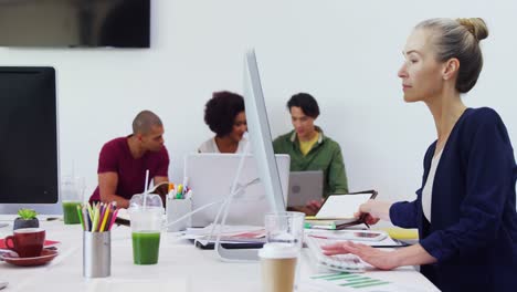 Woman-working-on-desktop-pc-with-colleagues-in-background-4k