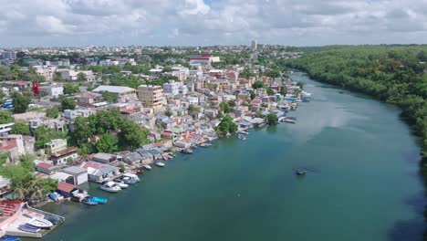 drone flight over tropical river in la romana city with parking boats at shoreline during sunlight on dominican republic