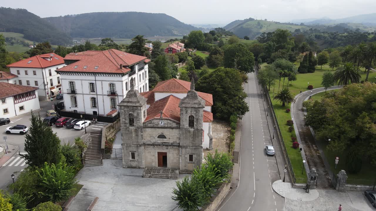 toma aérea de una antigua iglesia en colombres con montañas y campo verde en los alrededores