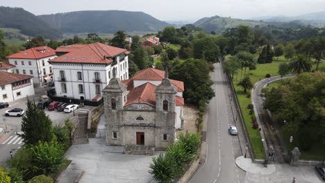 aerial shot of an old church in colombres with mountains and green countryside in the surrounding area