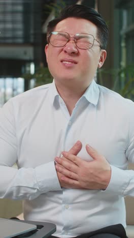 노트북을 사용하는 성숙한 사업가가 로비에서 심장마비로 가을 잡고 긴장해서 고통받습니다.