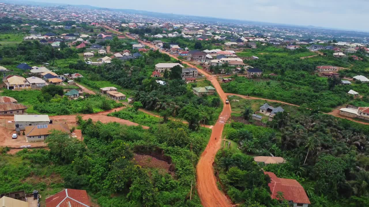 Aerial overview of a dirt road running to a distant town in rural Nigeria, Africa