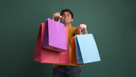happy ethnic young man showing shopping bags
