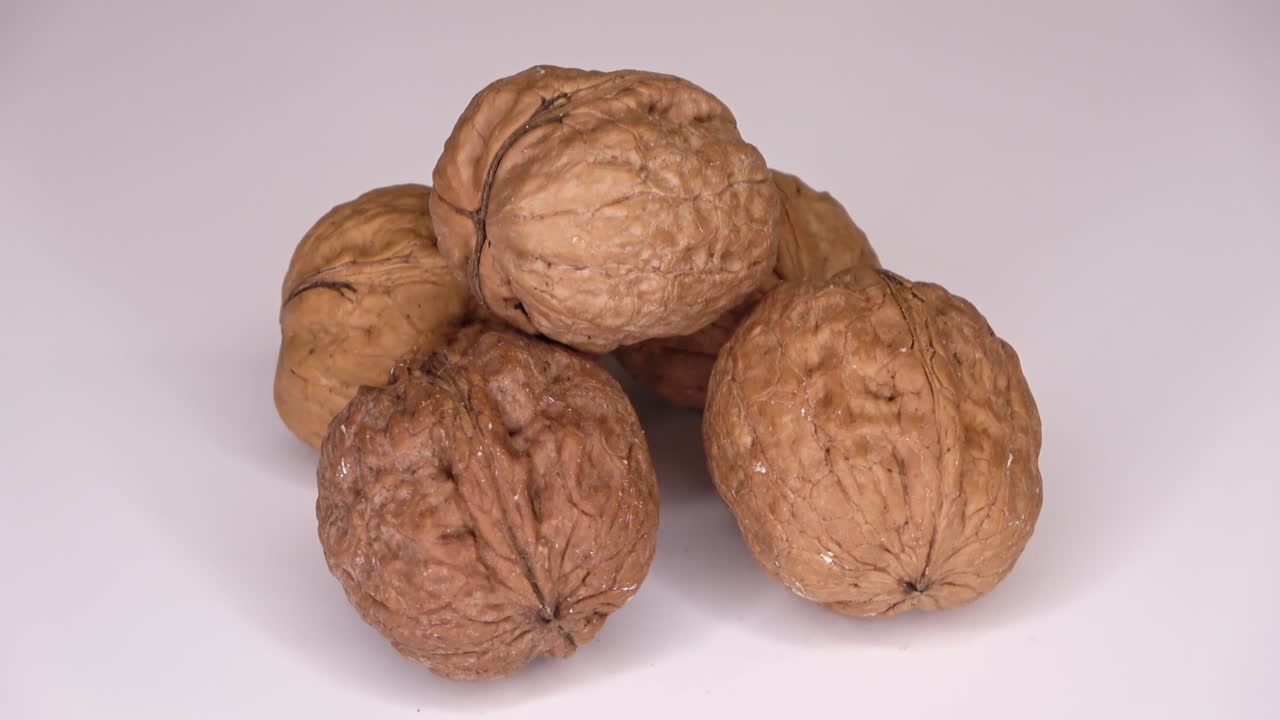algunas nueces giran lentamente en un círculo sobre un fondo blanco - video en bucle.