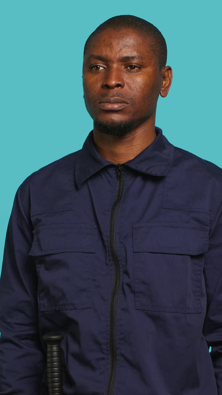 Uomo africano in uniforme blu scuro che tiene in mano un bastone