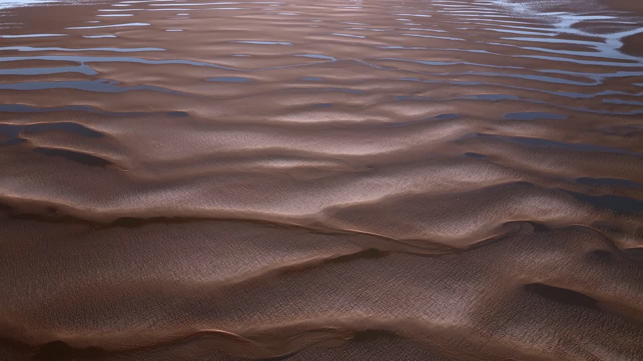 Sand patterns and interconnecting pools at sunset and low tide. Aerial view.