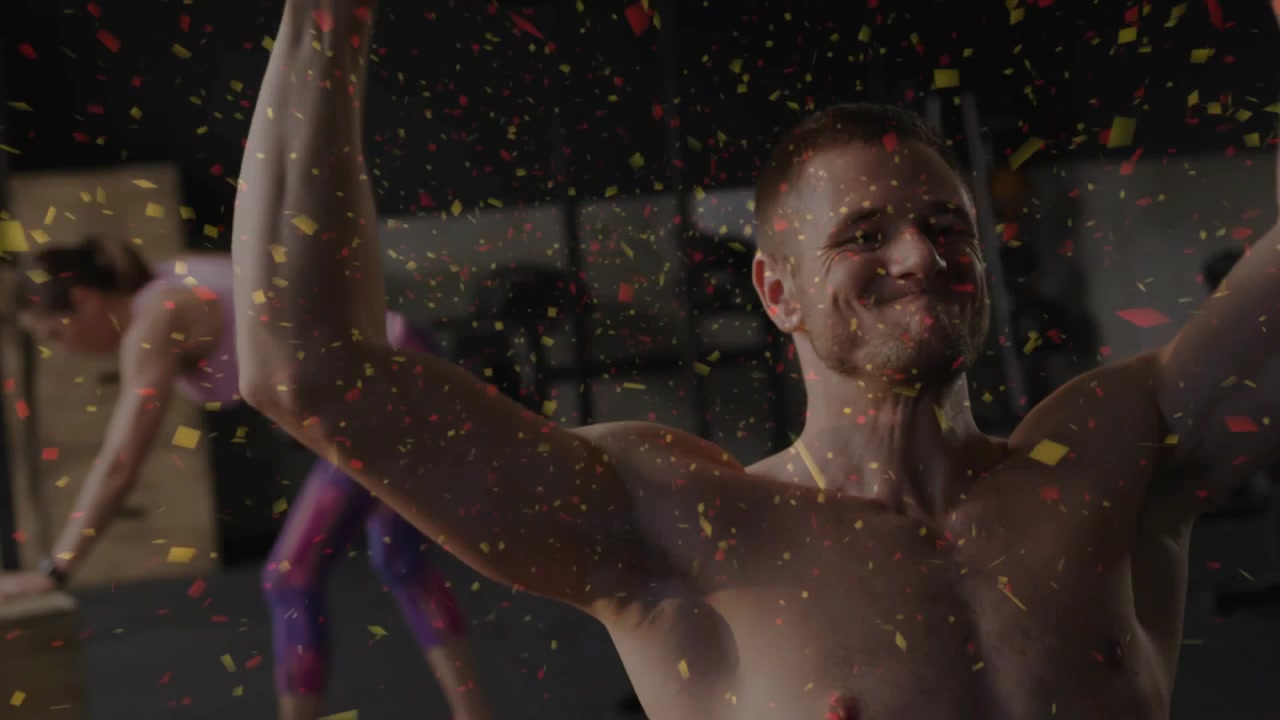 Man starting rep pressing dumbbell overhead in gym training, confetti overlay accentuating motion