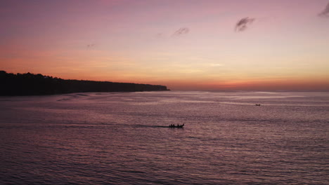 aerial view over people in a small fishing boat at sunset