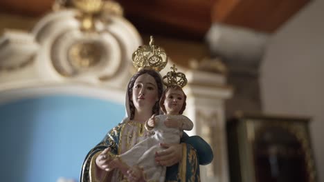 Statue-of-the-Virgin-Mary-holding-baby-Jesus,-both-wearing-crowns,-in-a-church-interior