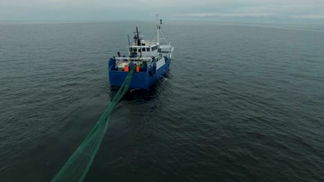 aerial shot of a commercial fishing ship that pulls trawl net