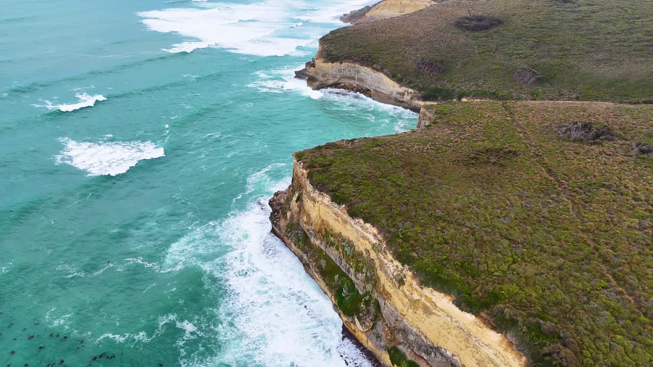Drone footage captures rugged cliffs and turquoise waves along Port Campbell's coastline under soft, natural lighting