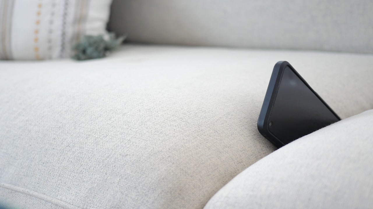 Black Smartphone Vibrating Between Sofa Cushions