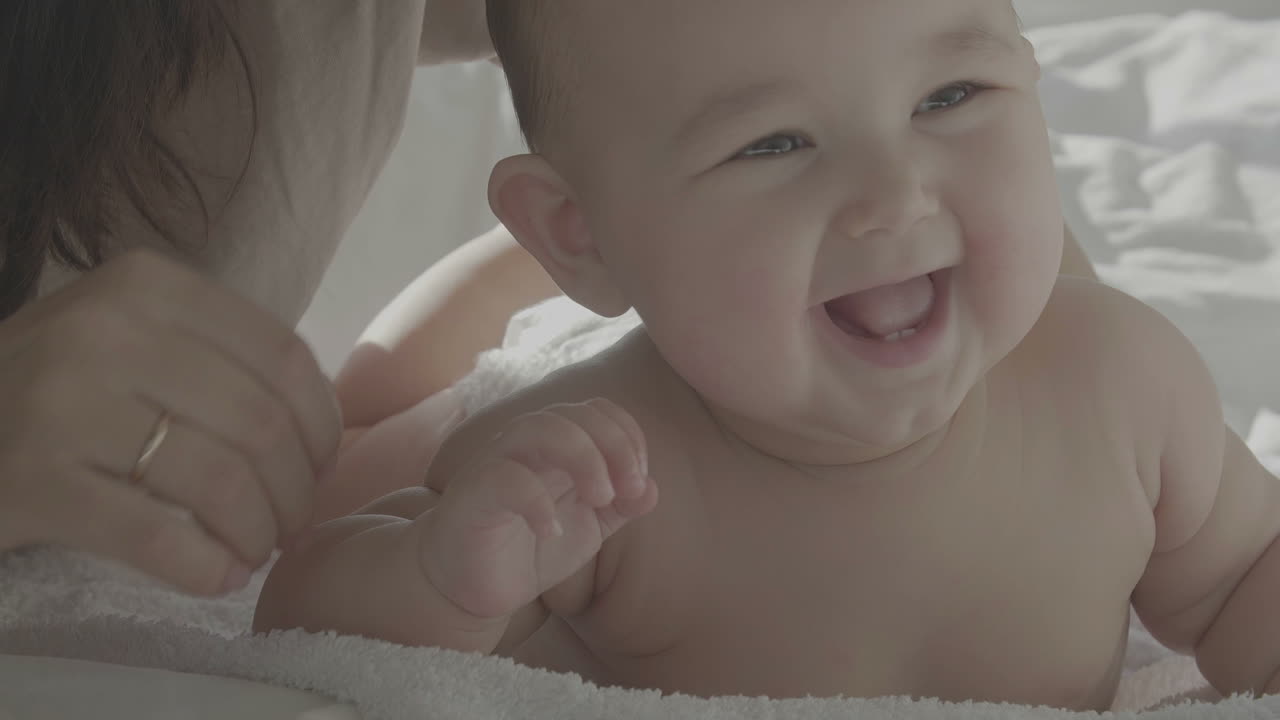 침대에서 엄마와 함께 웃는 귀여운 행복한 아기의 초상화