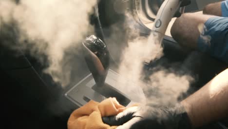 Hombre-Con-Guantes-Negros-Limpiando-El-área-De-La-Palanca-De-Cambios-Del-Coche-Con-Vapor