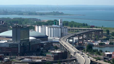 eine zeitraffer-luftaufnahme der stadt buffalo, new york, und ihrer infrastruktur aus brücken und gebäuden neben dem eriesee mit einigen windturbinen im hintergrund