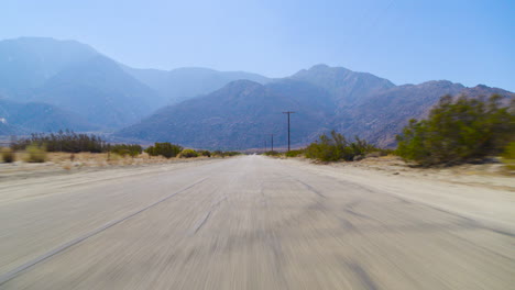 Palm Springs POV driving down the road with the rugged San Jacinto Mountains in the distance in California under a clear blue sky on a bright, sunny day