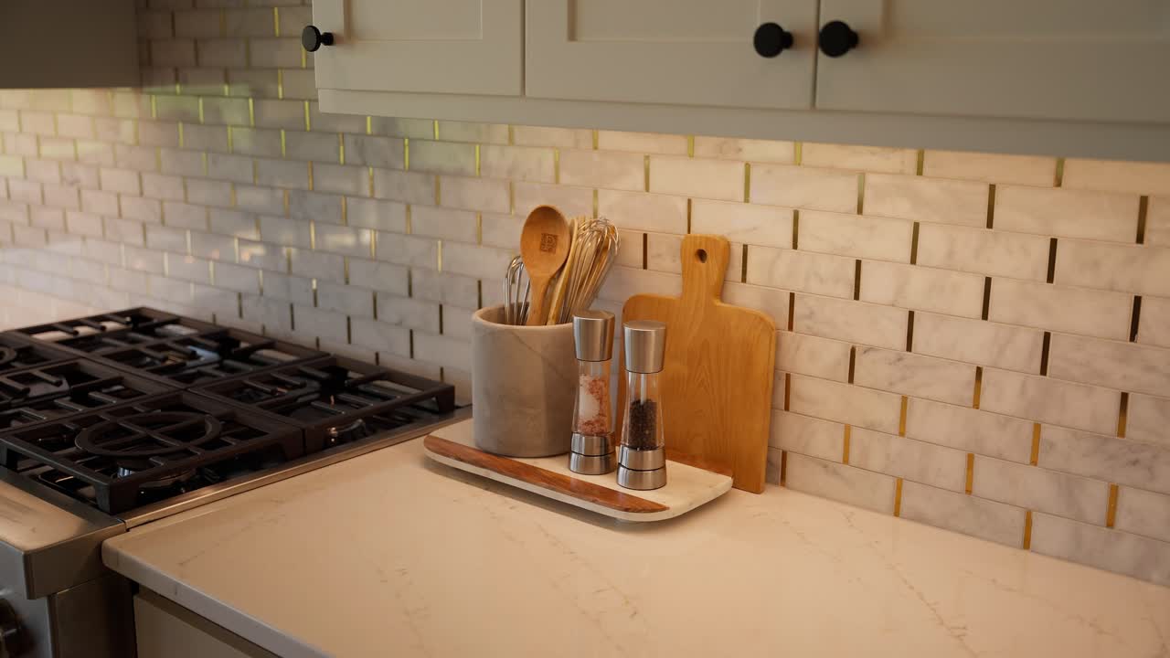 Close-up of cooking utensils, cutting board, salt and pepper shaker on kitchen countertop near stove
