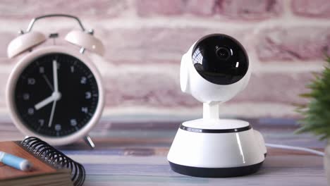 home security camera on desk with alarm clock