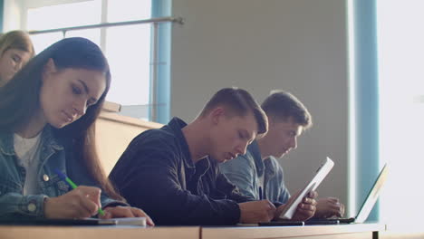 a group of male and female students in a large auditorium of the university listen to a lecture by a professor.