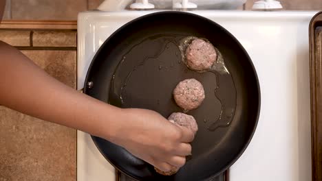 putting ground lamb balls into a frying pan to make spiced patties - overhead view lamb patty series