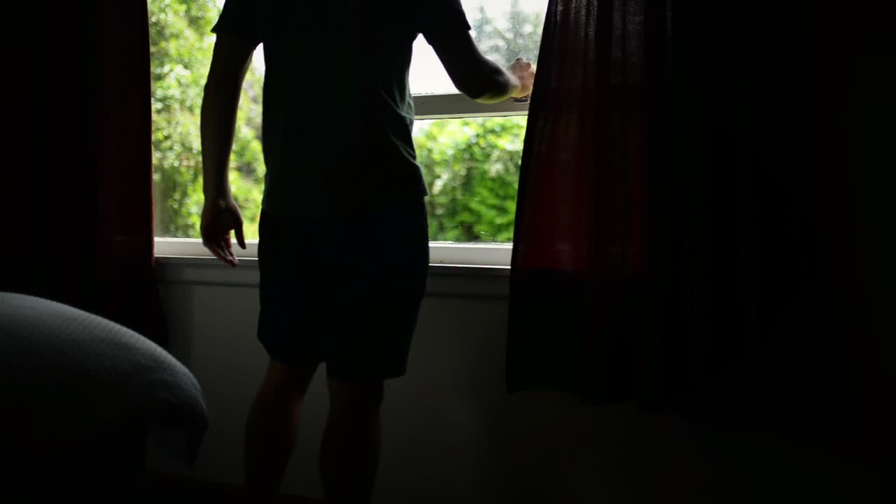 커튼을 밀고 침실 창문을 향한 정원을 여는 청년