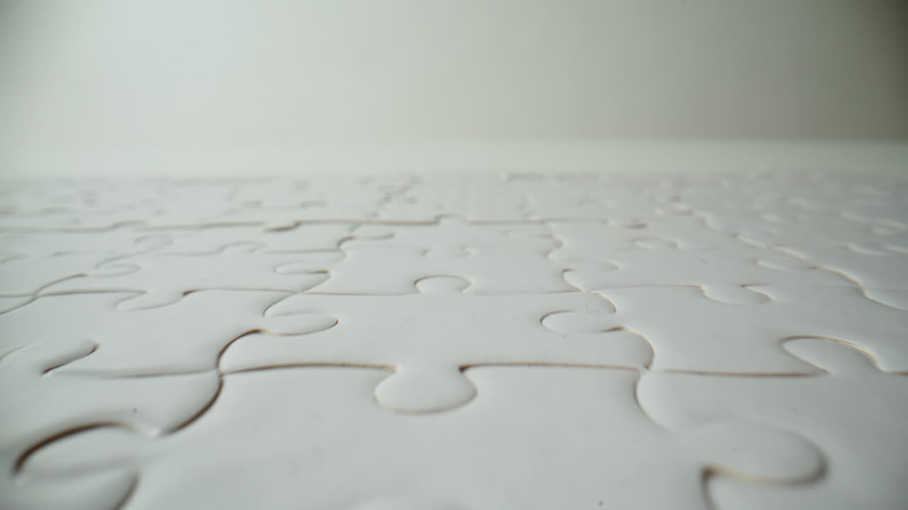 Closeup white completed puzzle placed on empty table. Jigsaw teaser zoom on