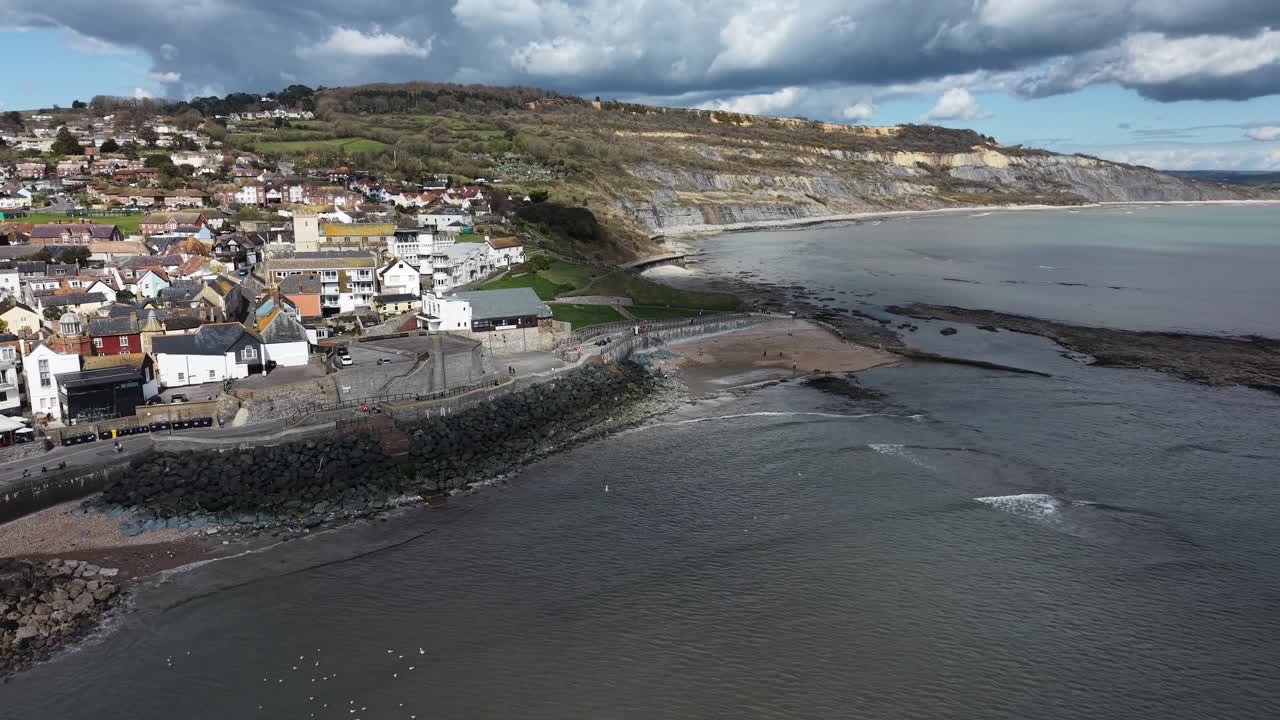 Orla marítima de Lyme Regis, falésias de The Spittles ao fundo, vista aérea de drone.