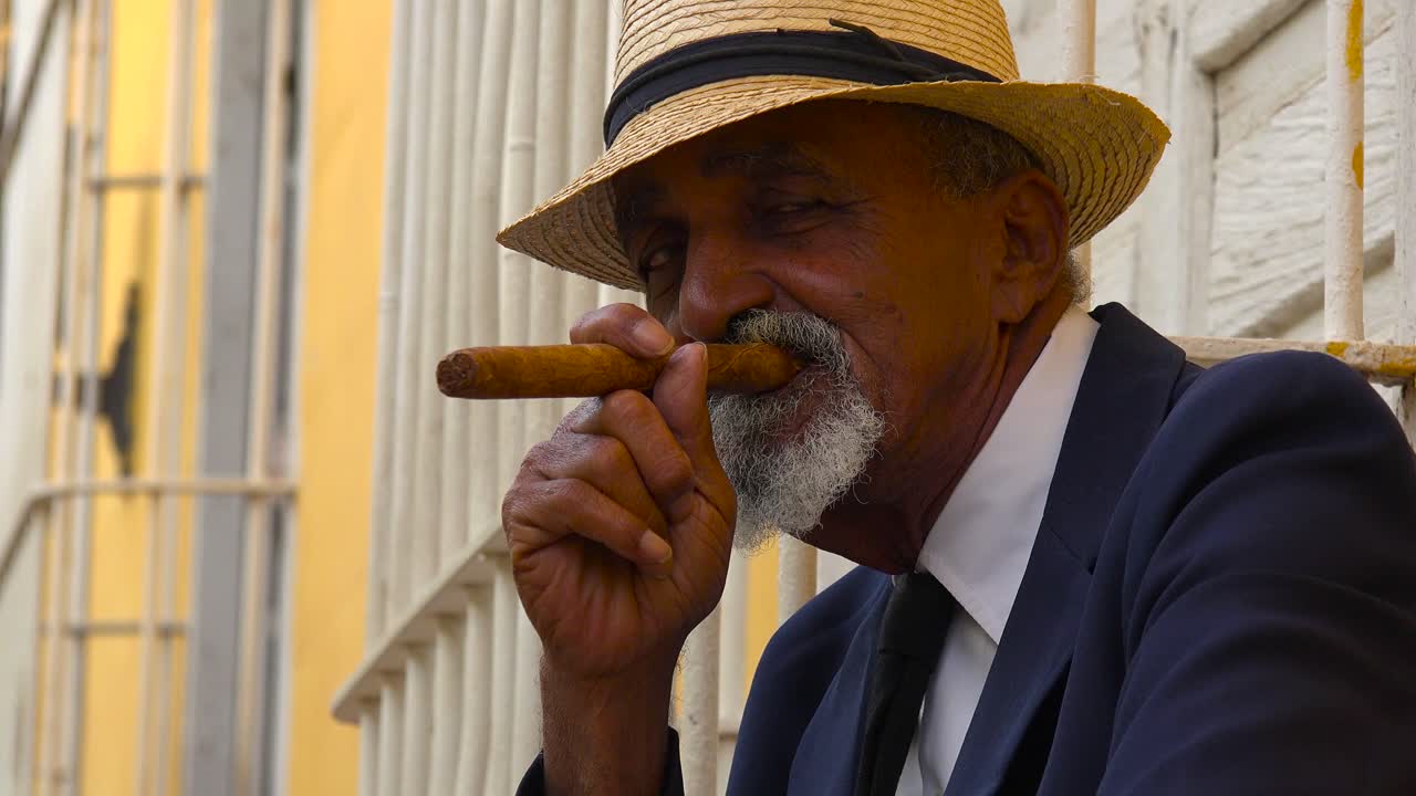 un hombre cubano fuma un cigarro en las coloridas calles de trinidad cuba