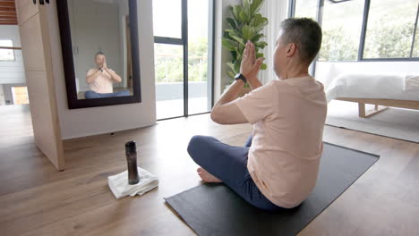 senior biracial man practicing yoga meditation at home