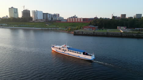 passenger riverboat cruising on a river with city skyline in background
