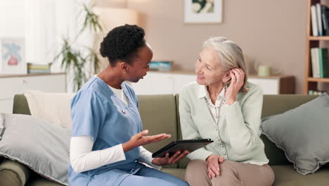 caregiver assisting senior woman with tablet at home