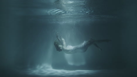 a girl in a white dress falls under the water