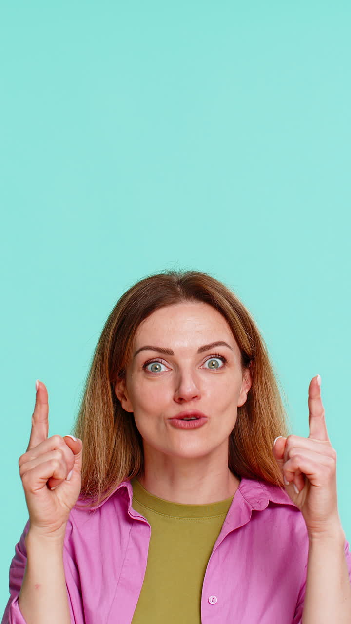 Woman pointing up with serious expression drawing attention to important thing or key information