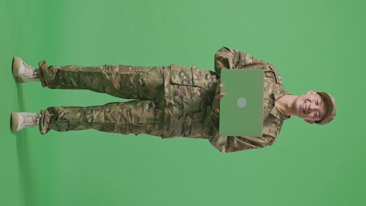 Full Body Of Asian Man Soldier Using A Laptop And Smiling While Standing In The Green Screen Background Studio