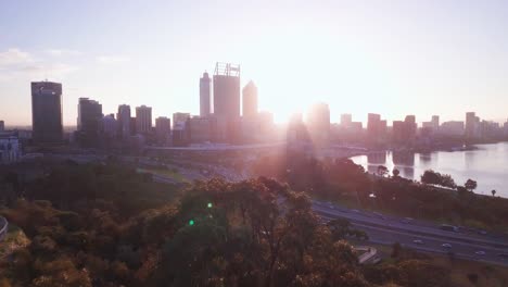 Vista-Aérea-De-Un-Horizonte-De-Perth-Al-Amanecer-Con-Haces-De-Luz-Con-Movimiento-De-Cámara-Hacia-Adelante