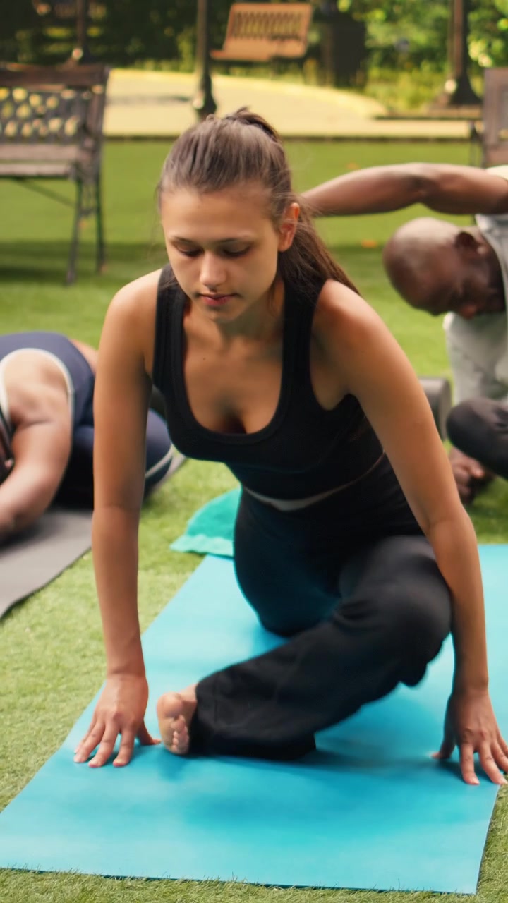 Vertical Video Woman stretching in forward fold position with eyes closed during yoga class