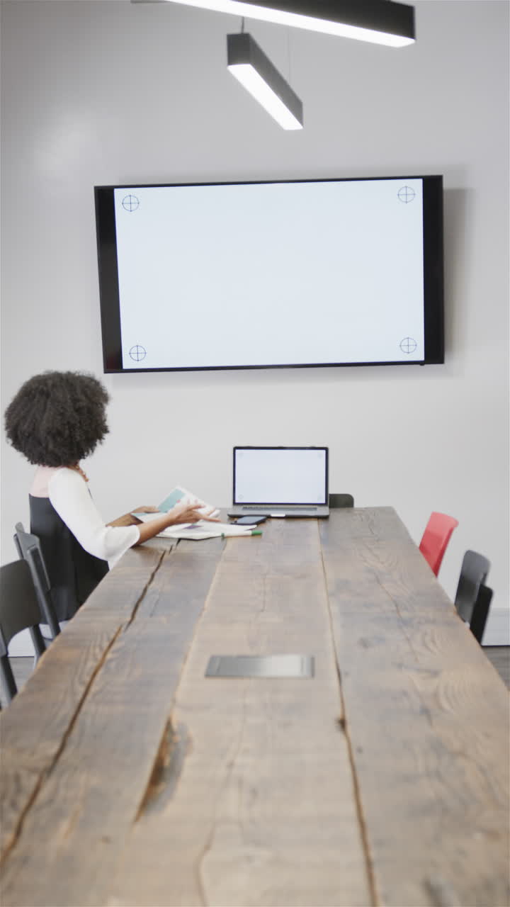 Biracial businesswoman in casual attire on video call in office meeting room, copy space