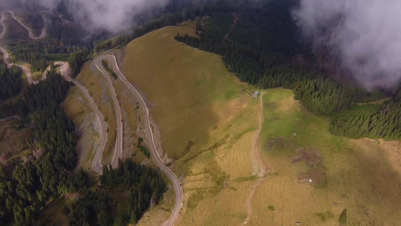Beautiful aerial view of misty mountain valley scenery with village from a drone flying forwards on misty morning in Carpathian Mountains, Ukraine. Cinematic drone shot of countryside scene in morning