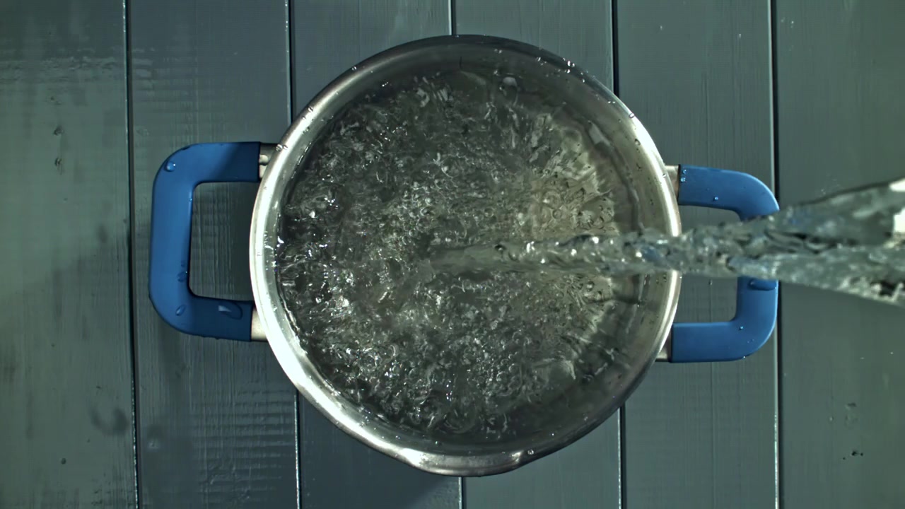 Acqua che si versa al rallentatore in una pentola di acciaio inossidabile