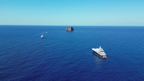 boats and strombolicchio volcano island at stromboli, aeolian islands, sicily, italy - aerial 4k